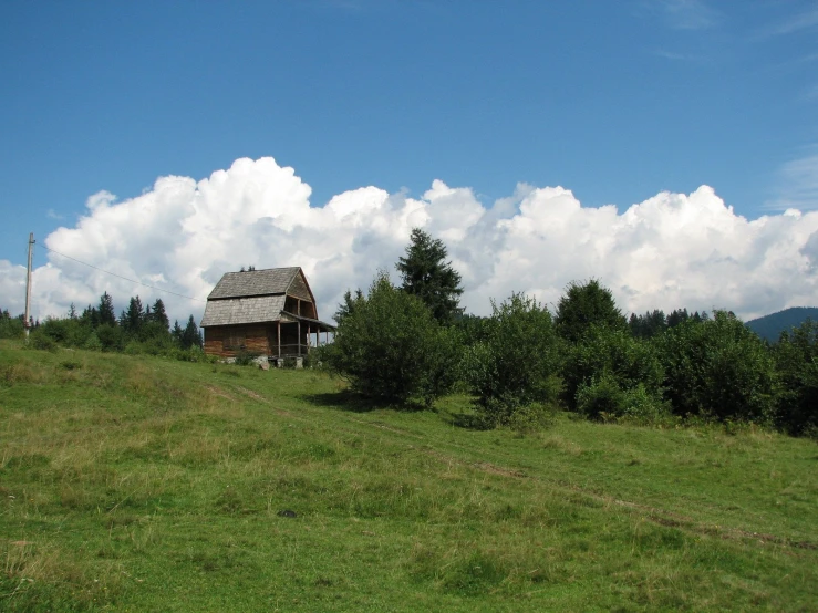 a large green hill with a wooden house on it