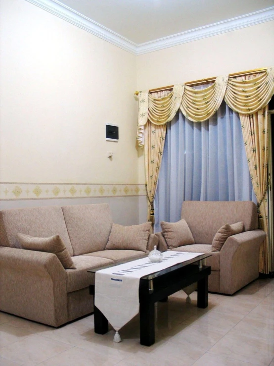 a room with beige couches, curtains and a table