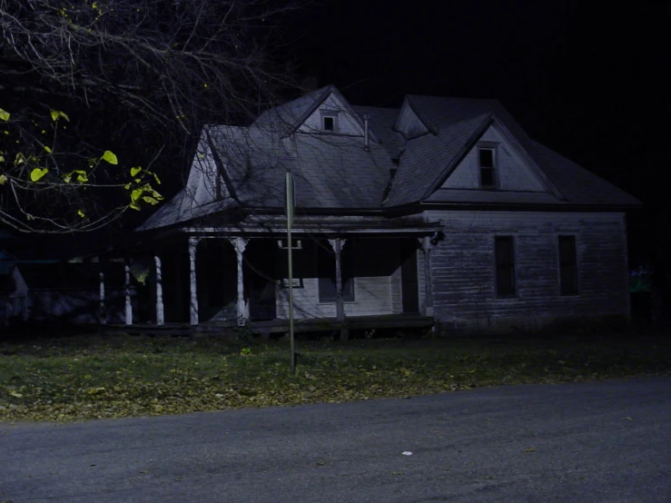 old house with an extended porch and covered porch at night