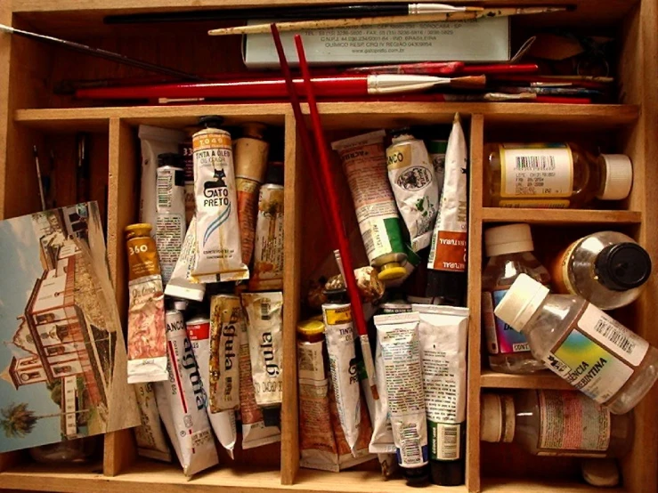 a wooden box that has various art supplies and brushes