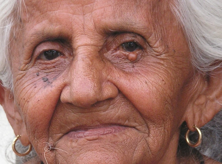 an elderly woman with piercings on her face looks over her shoulder