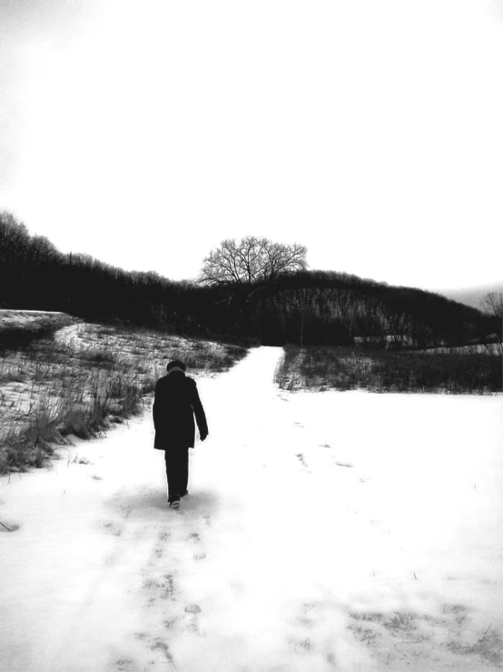 a man is walking in the snow in black and white