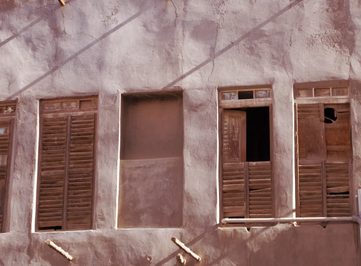 two brown window with shutters closed next to a wall