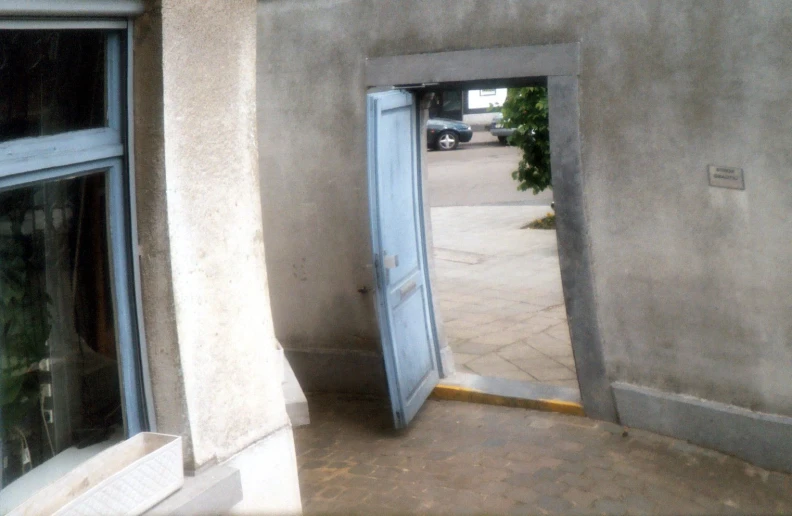 an open door leading to another building with cars behind