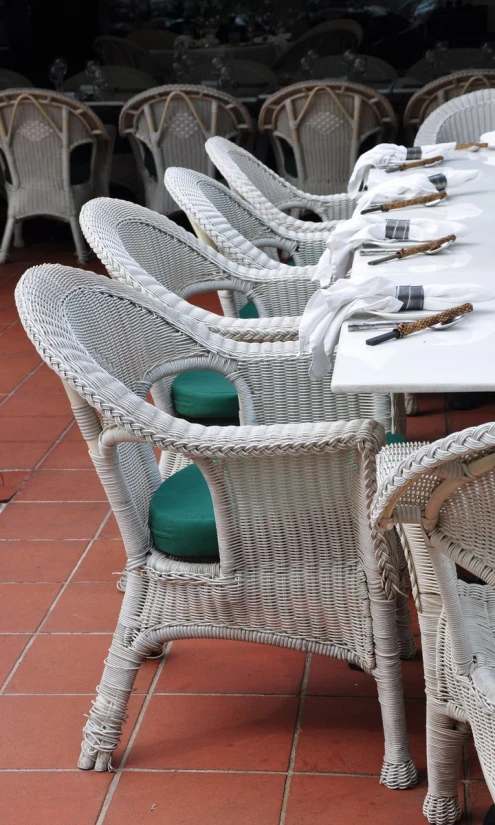 a row of wicker dining tables sitting on red brick flooring