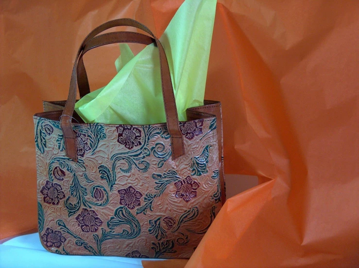 an open brown bag with orange and green folded up items in it