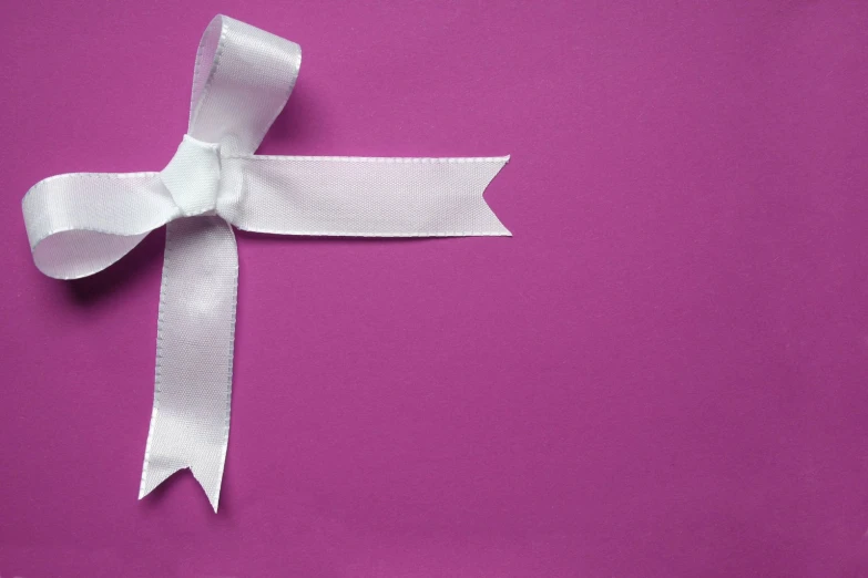 a white ribbon tied in a bow on a purple background