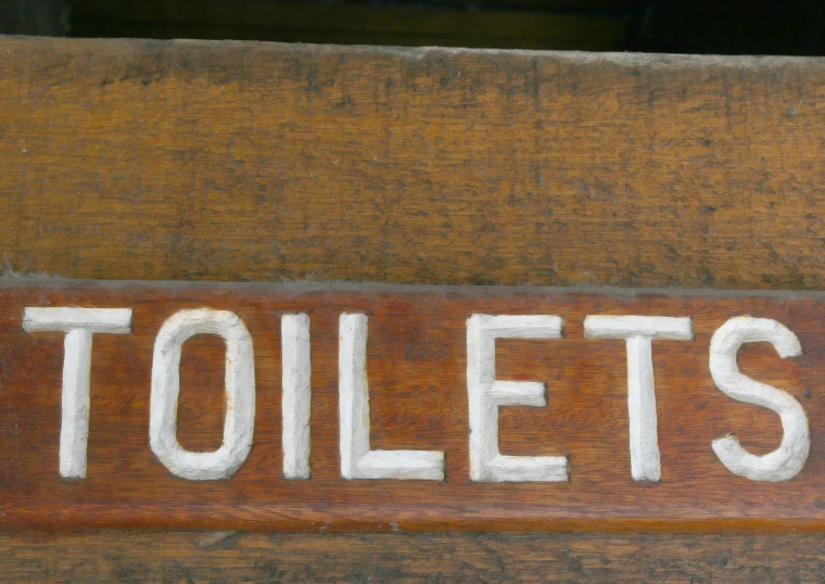 a wooden sign with the word toilets written on it
