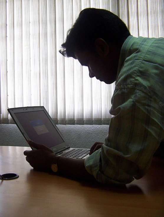 a man sitting on his laptop computer looking at it