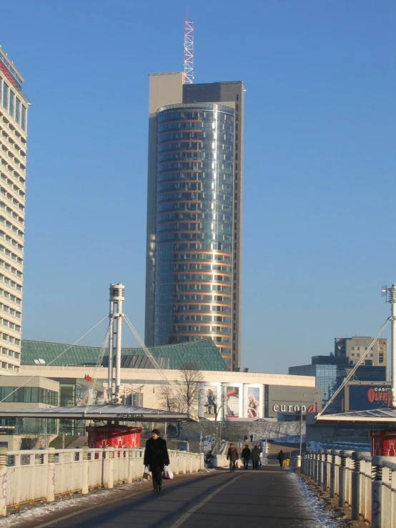 a man on a bicycle going over an open bridge towards a high rise building