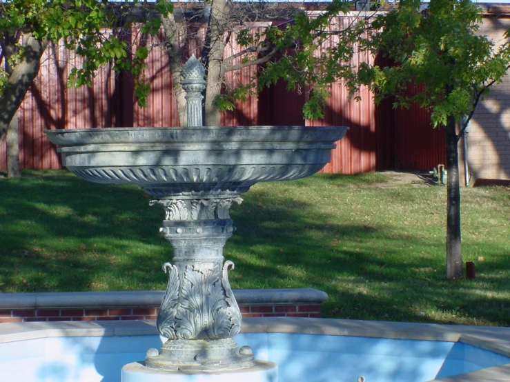 an ornate, grey garden fountain in a yard