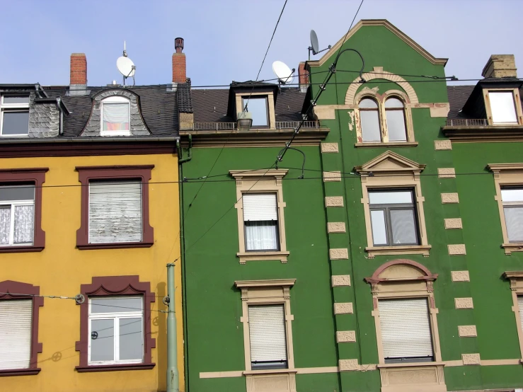 a row of buildings with windows painted green and yellow