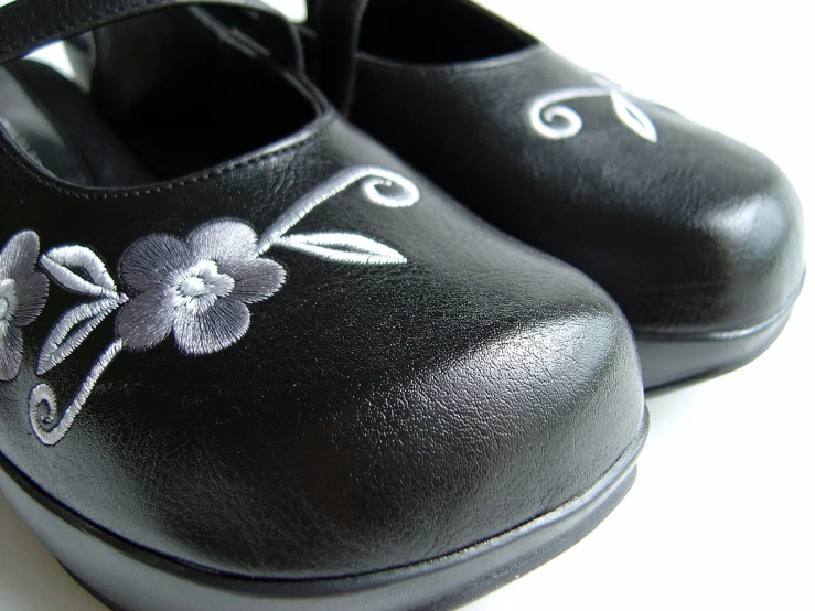 two shoes with embroidered flowers are shown on the floor