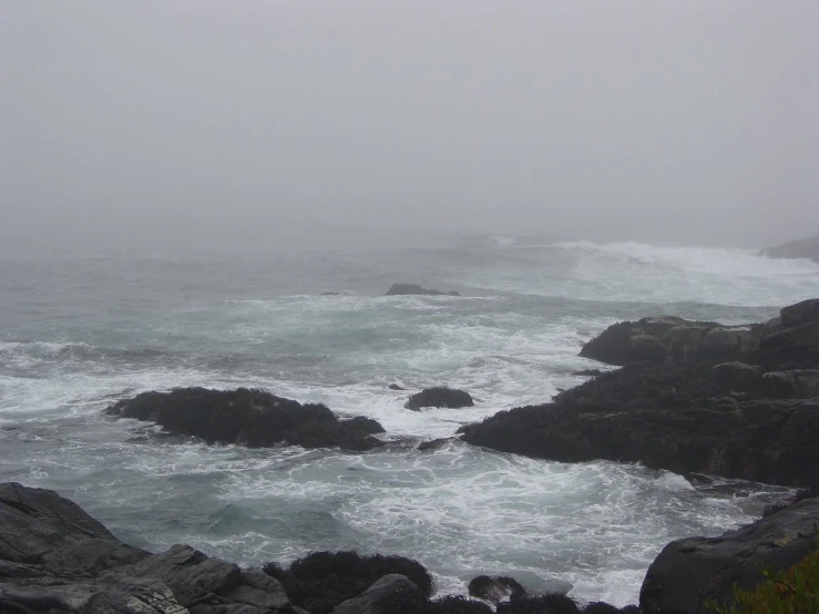 a couple of rocks sitting on top of a beach covered in fog