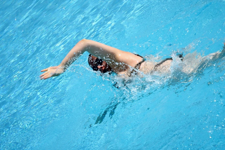 a man wearing goggles swims in a swimming pool