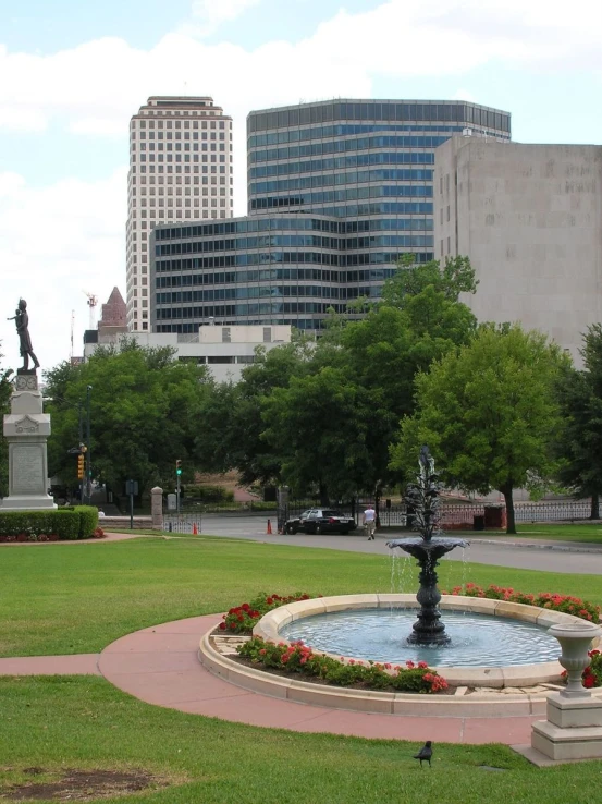 this is an urban park with a fountain and flowers in it