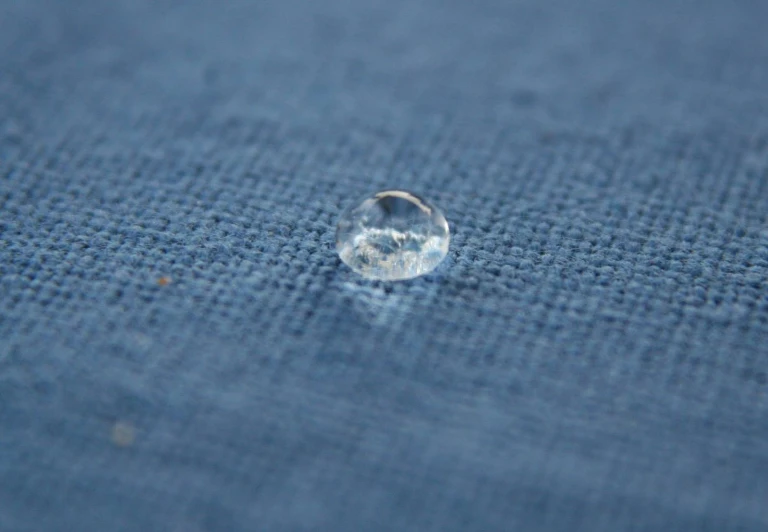 a droplet of clear water sits on the cloth