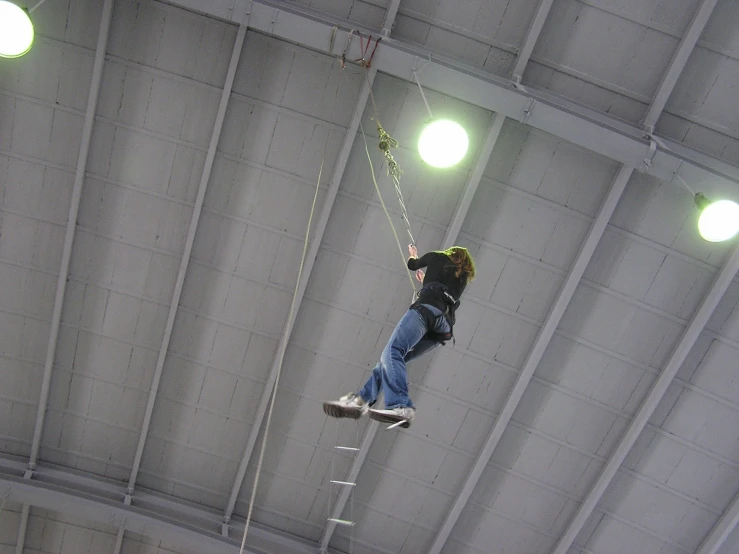a man on a rope climbs up to the ceiling