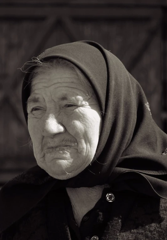 an old woman with a surprised look wearing a head scarf
