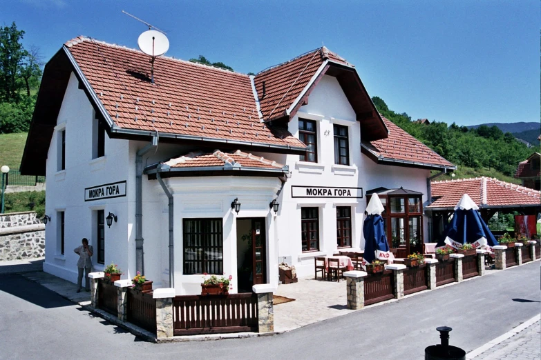 the white restaurant has many wooden tables outside of it