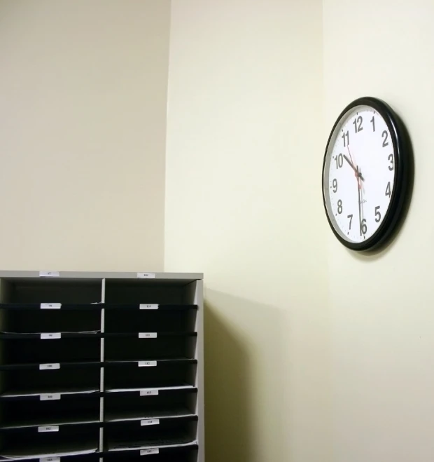 a clock on the wall next to black plastic containers