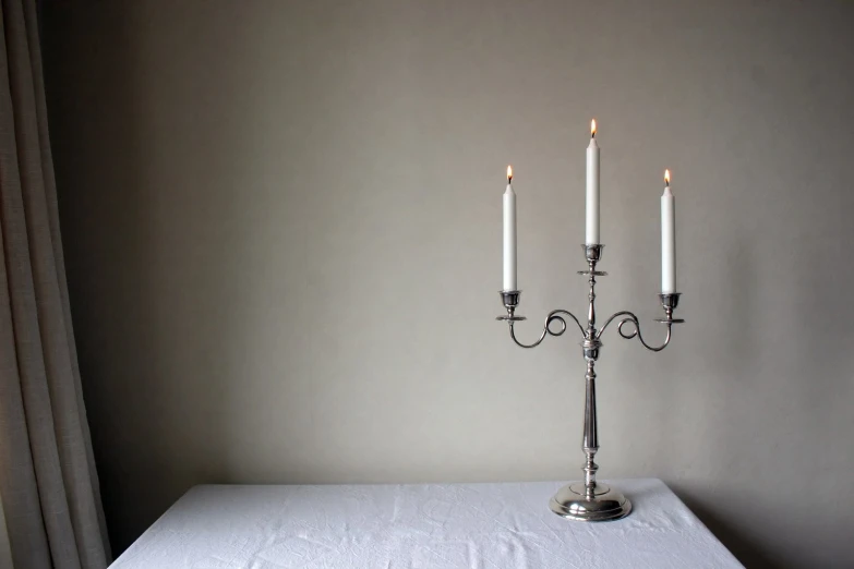 three candle - lit lights on top of an empty table