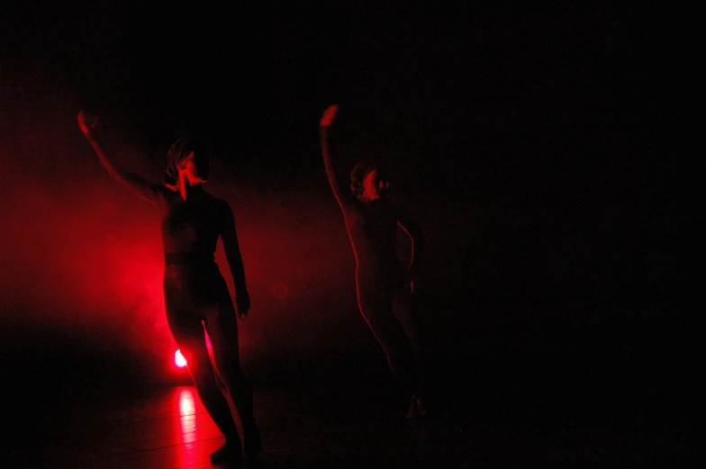 two people on a stage one in the dark dancing