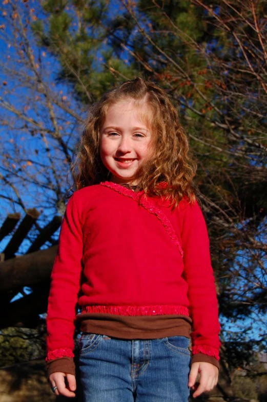 a  wearing a red sweater smiles at the camera