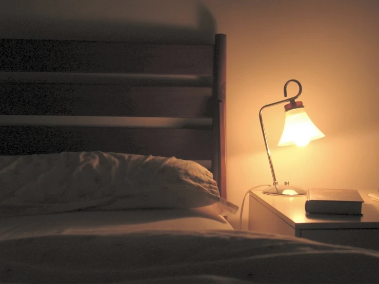 a lamp is lit on a table next to the bed