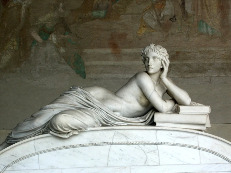 a very pretty statue sitting on a ledge with her eyes closed