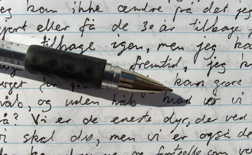a pen laying on top of a paper with writing on it
