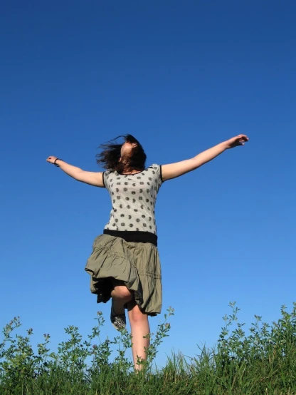 a woman is jumping in the air with her arms outstretched