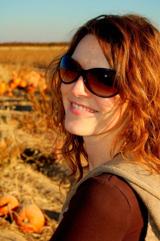 the girl is enjoying the day in the pumpkin patch