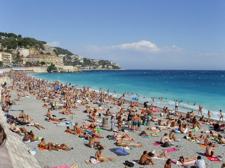 a very crowded beach with lots of people relaxing and swimming