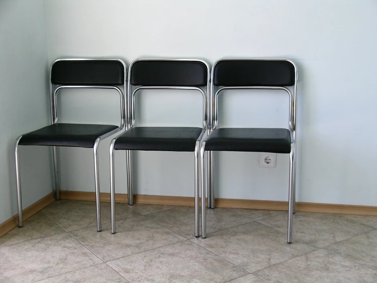 three black leather chairs lined up against a wall