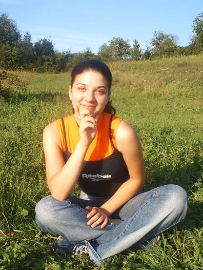 a girl sitting in a field wearing a black top