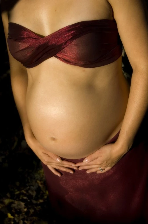 a pregnant woman is wearing a red bikini top