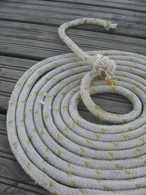 a white rope with yellow and white dots is on a dock