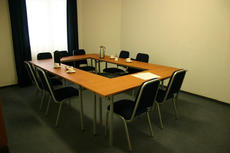 a long table surrounded by black chairs with windows