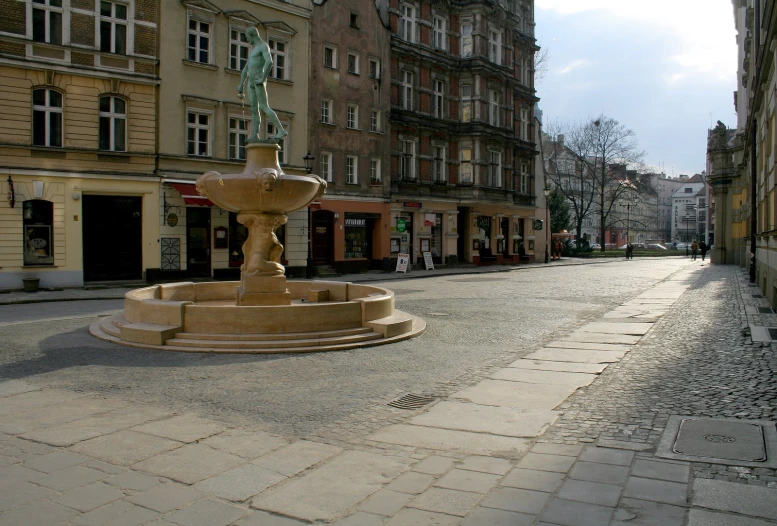 there is an empty cobble stone street and water fountain