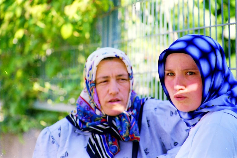 two women in veils one is looking at the camera and one is staring at a camera