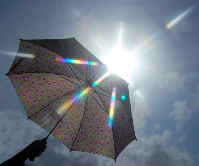 sun shining through the umbrella's canopy of a clear sky