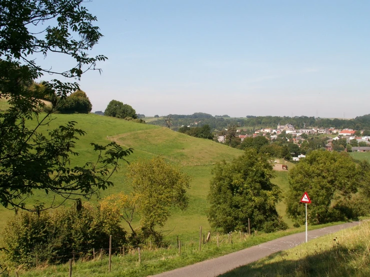 a winding country road with a green hillside in the background