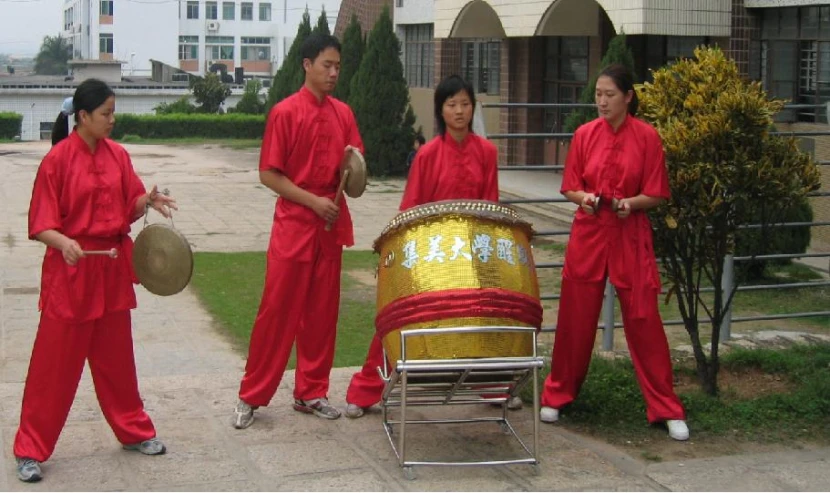 four people in red are playing drums and drum on the side walk
