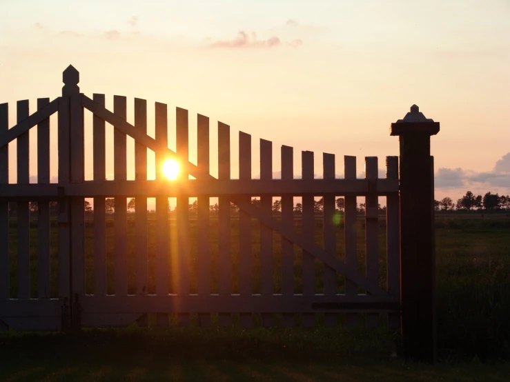 the sun peeking out behind the picket fence