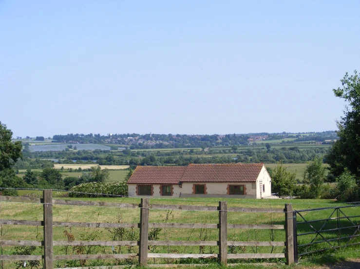 a small house and two wooden gates sit in front of a field
