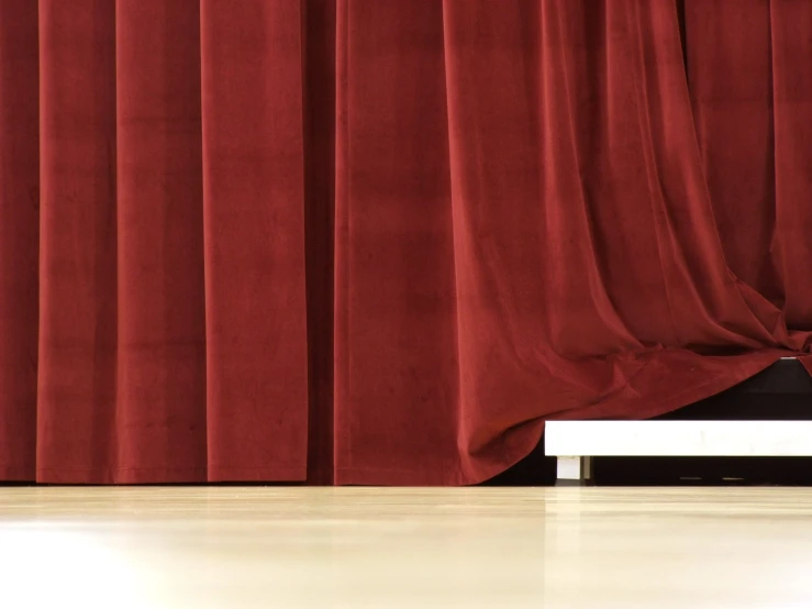 a red curtain with dark wood floor and white bench