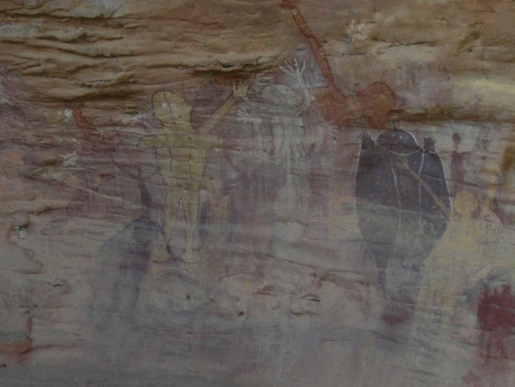 a rock wall painting showing some people walking around with umbrellas