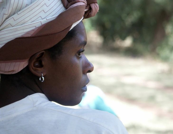 a woman with a hat on the top has a big earring