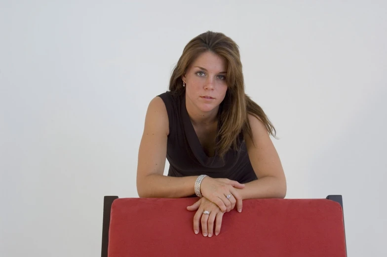 a woman sitting at a table with her arm on top of a red chair